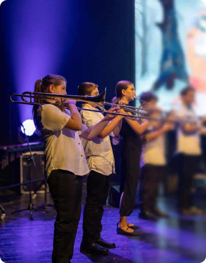 group of young girls passionately playing trombones on stage at Yizre'el Gilboa Music Center brass ensemble rehearsal